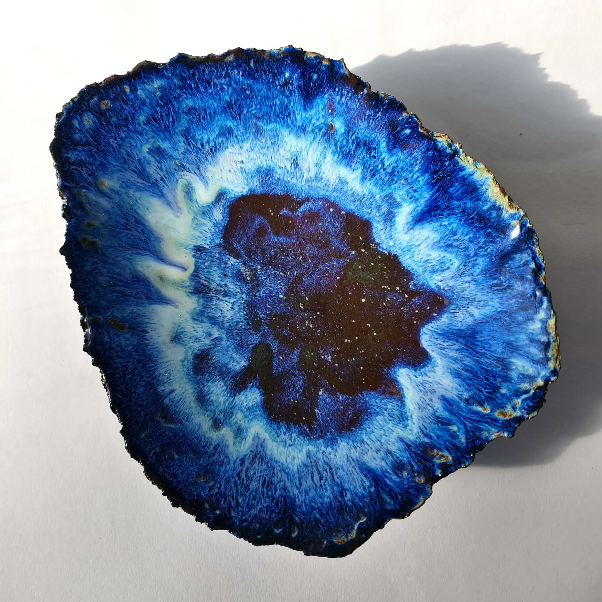 Sculptural bowl in black porcelain with layered blue floating glazes and textured exterior