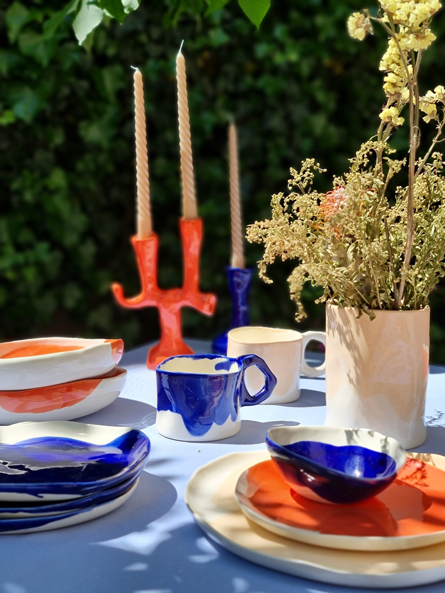  Outdoor table setting with handmade blue and orange ceramic tableware by Pottery & Poetry.